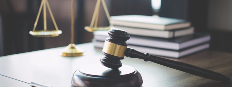 Scales of justice and Gavel on wooden table and Lawyer or Judge working with agreement in Courtroom, Justice and Law concept.